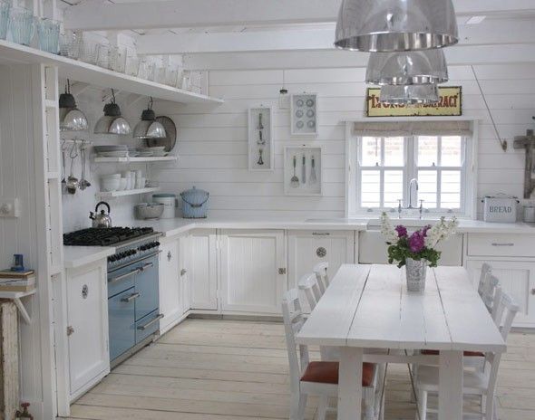 aranżacja kuchni w rustykalnym stylu,biała kuchnia z niebieską kuchenką i piekarnikiem,tradycyjna kuchnia w białym kolorze,srebrne lampy nad stołem w kuchni,biały stół w kuchni