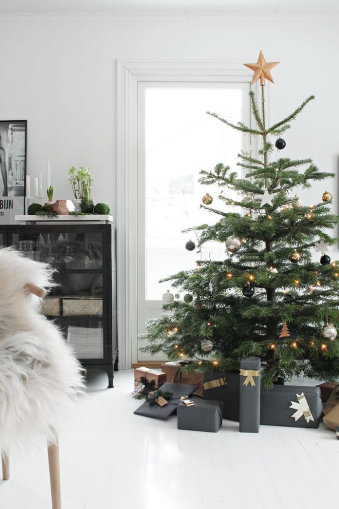 czarny kolor w dekoracjach świątecznych,czarne opakowania prezentów świątecznych, zielona choinka z czarnymi detalami ,biało-czarne wnętrze salonu w stylu skandynawskim z zieloną choinką