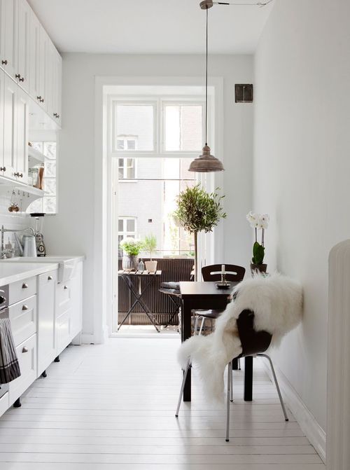 wąska kuchnia w białej aranżacji,jak urządzić wąską kuchnię w stylu skandynawskim,czarny stół i krzesła w kuchni,stół przy ścianie w małej kuchni