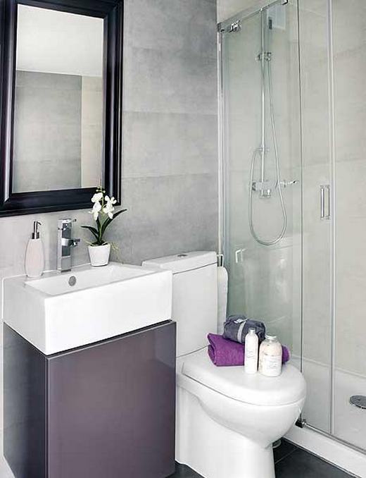 czarne ramy lustra,szara łazienka,aranżacja małej łazienki,łazienka w szarym kolorze,szklane półki w łazience,fioletowe ręczniki