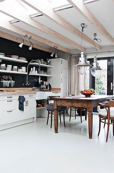 czarna ściana w białej kuchni,drewniany stół na białej podłodze,drewniane belki w kuchni,skandynawska kuchnia z rustykalnymi detalami