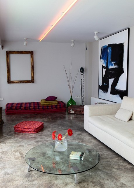 nowoczesny salon,czerwone siediska,biała sofa,złote ramy,nowoczesne grafiki,sklany stolik,kamienna podłoga,zielona butla,listwa oświetleniowa